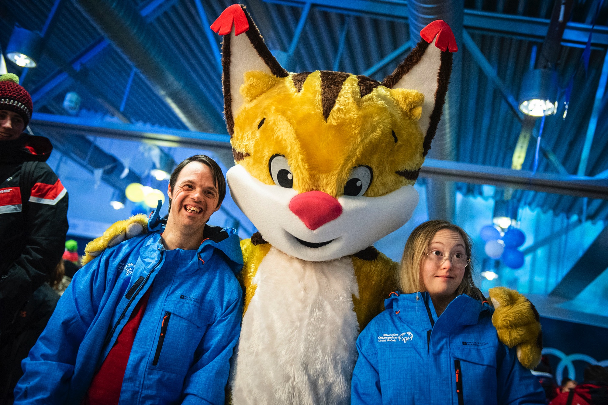 Maskoten Speci-Lo håller om två idrottare från Storbritannien som precis anlänt till Åre Östersund airport och Special Olympics Sweden Invitational Games 2020.