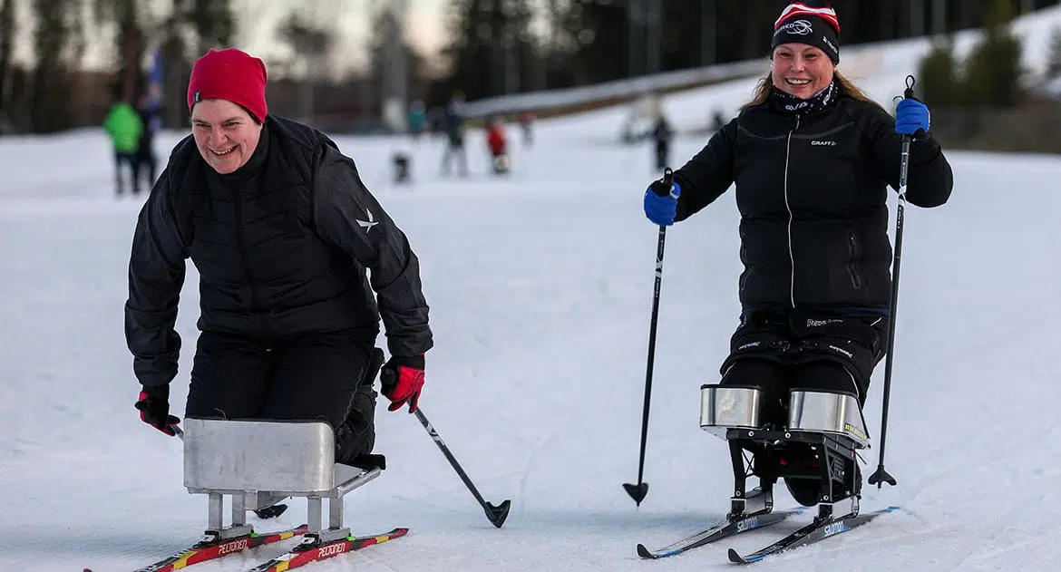 2 glada personer testar knästående längdskidor