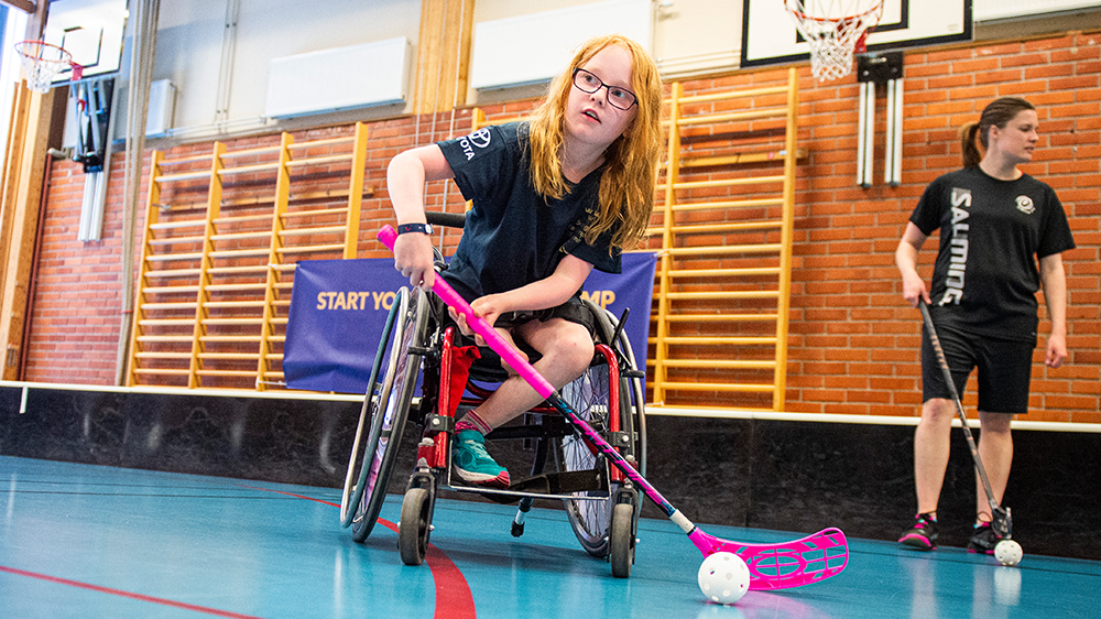En flicka som spelar rullstolsinnebandy.