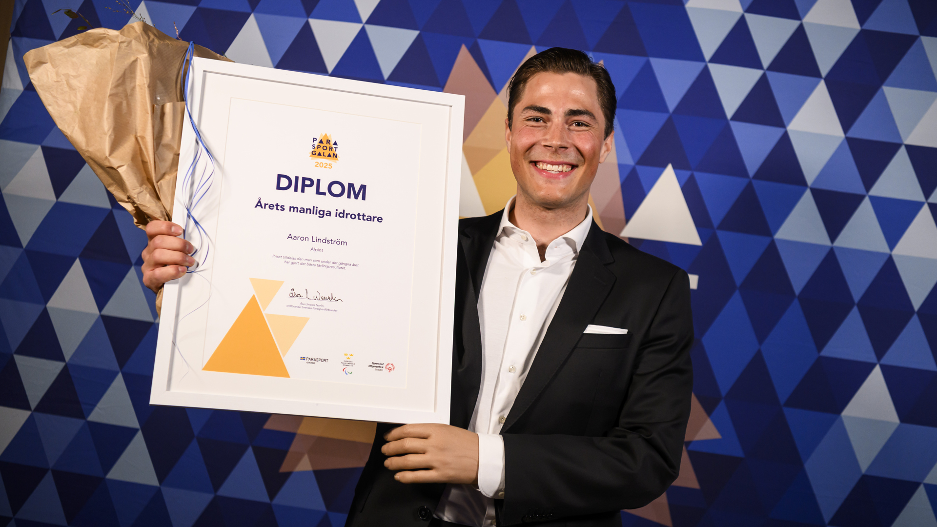 Aaron Lindström med diplom och blommor.