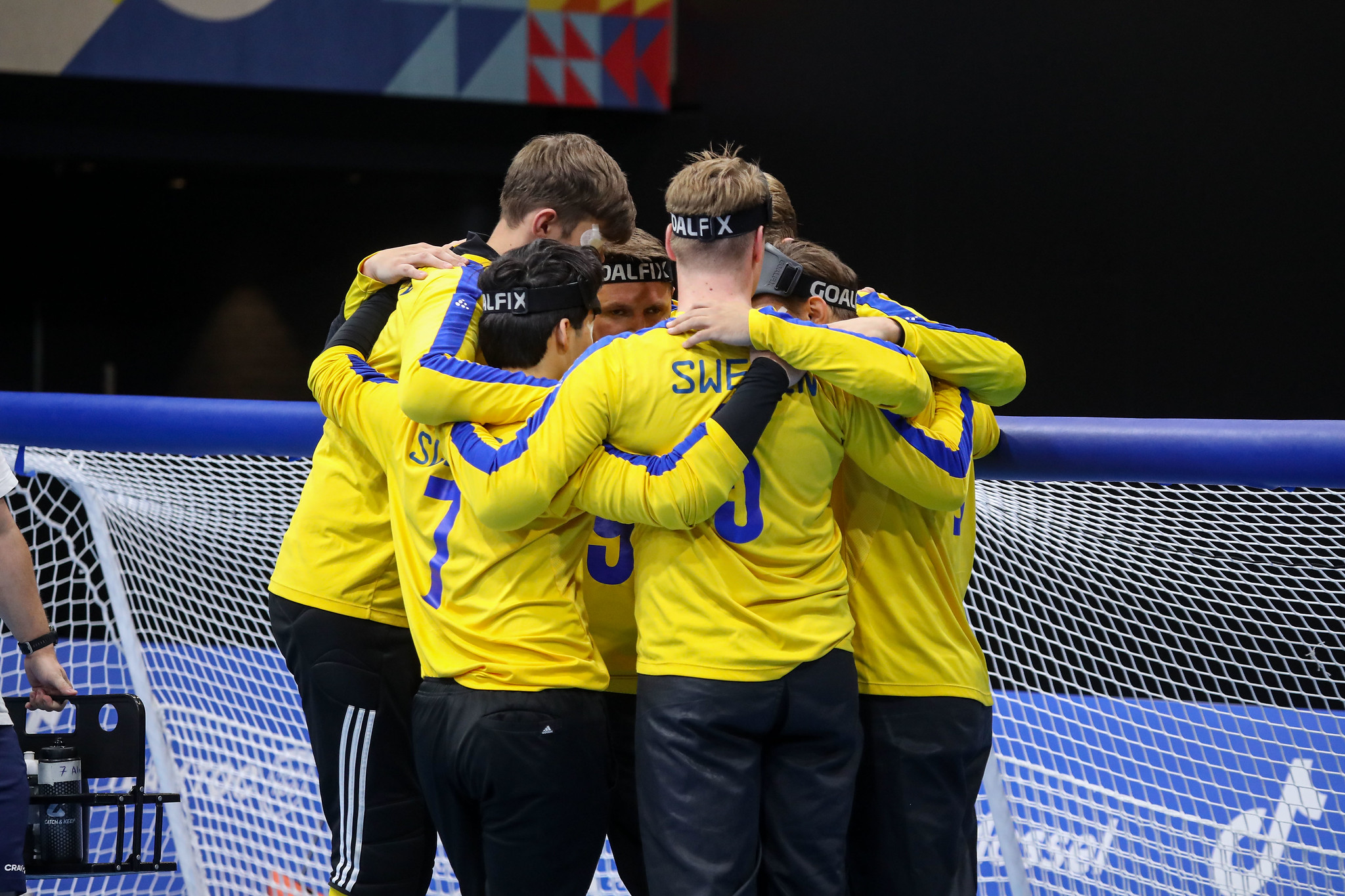 Landslaget i goalball håller om varandra i en klunga.
