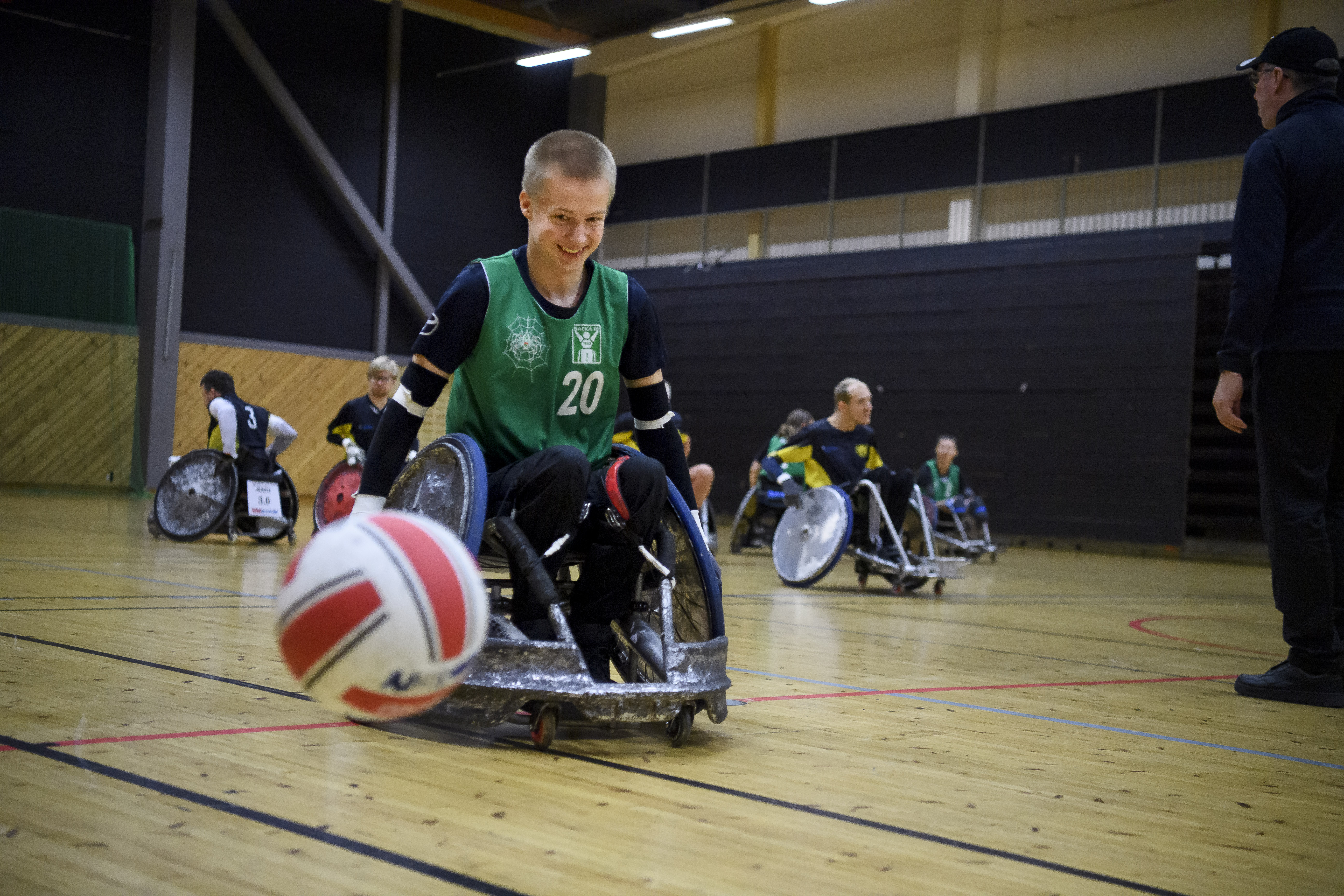 Bild på en kille i rugbyrullstol som jagar efter en boll. Han ser glad ut.