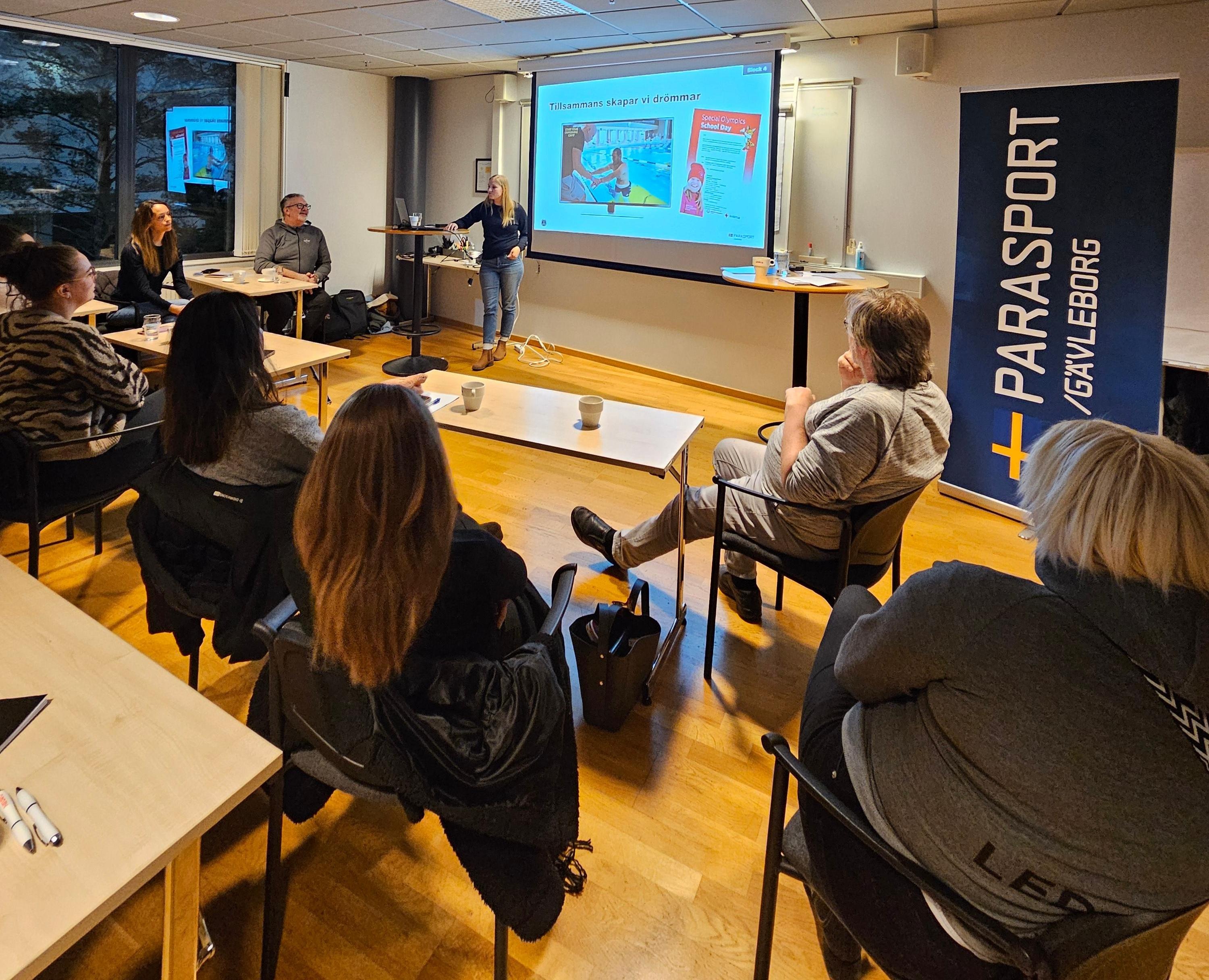 Utbildning av Parasportens Grunder i en lokal. Flera deltagre sitter ner och tittar på Elin Walfridsson som föreläser.