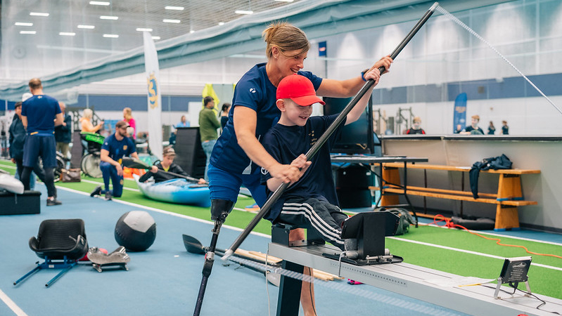 En ledare instruerar en ung kille hur man paddlar.
