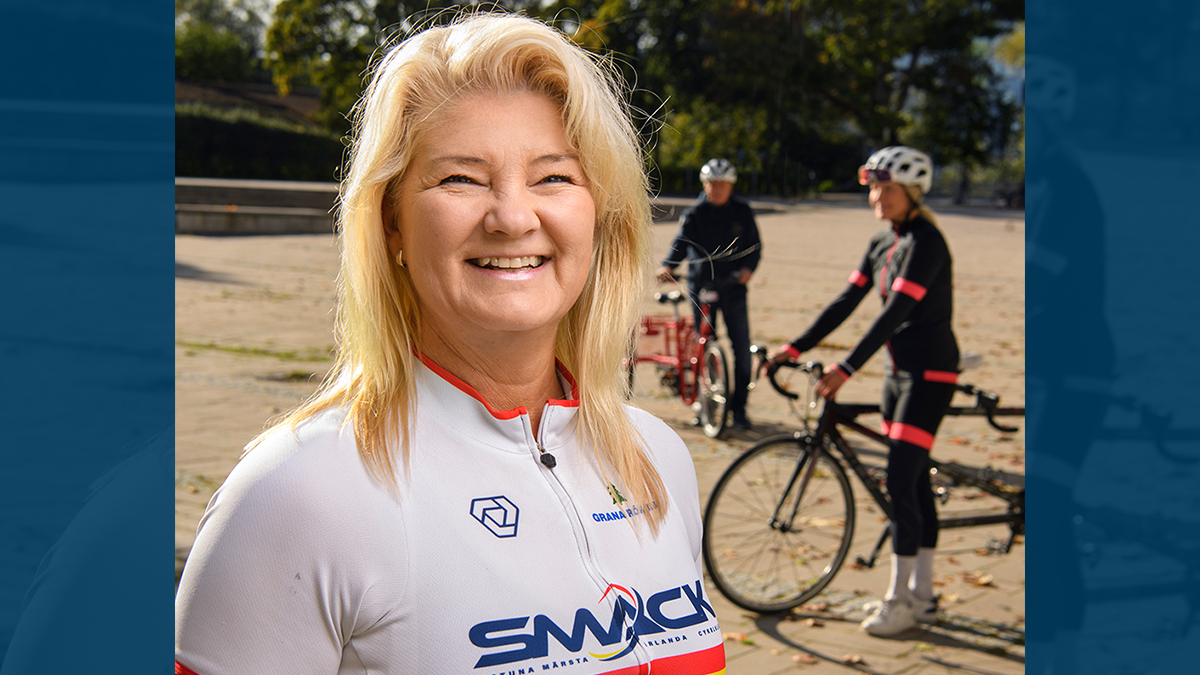 Eva Zahawi ler och tittar in i kameran. I bakgrunden syns flera cyklister.