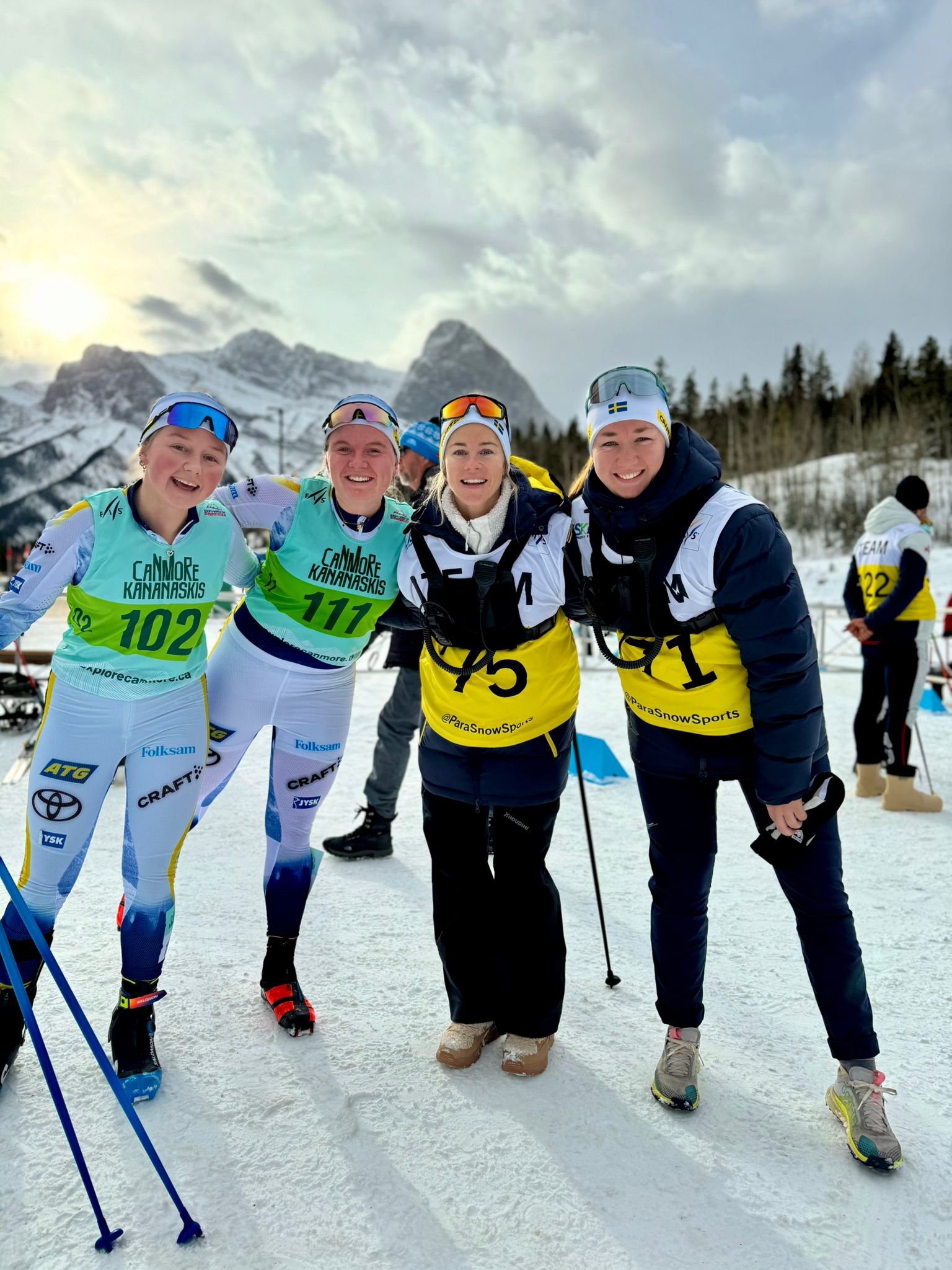 Åkarna Ellen och Alice tillsammans med ledare. I bakgrunden syns snötäckta berg.