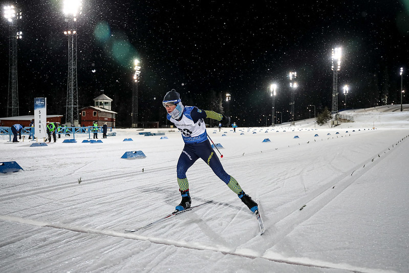 Stående skidåkare skejtar på skidstadion en mörk kväll.