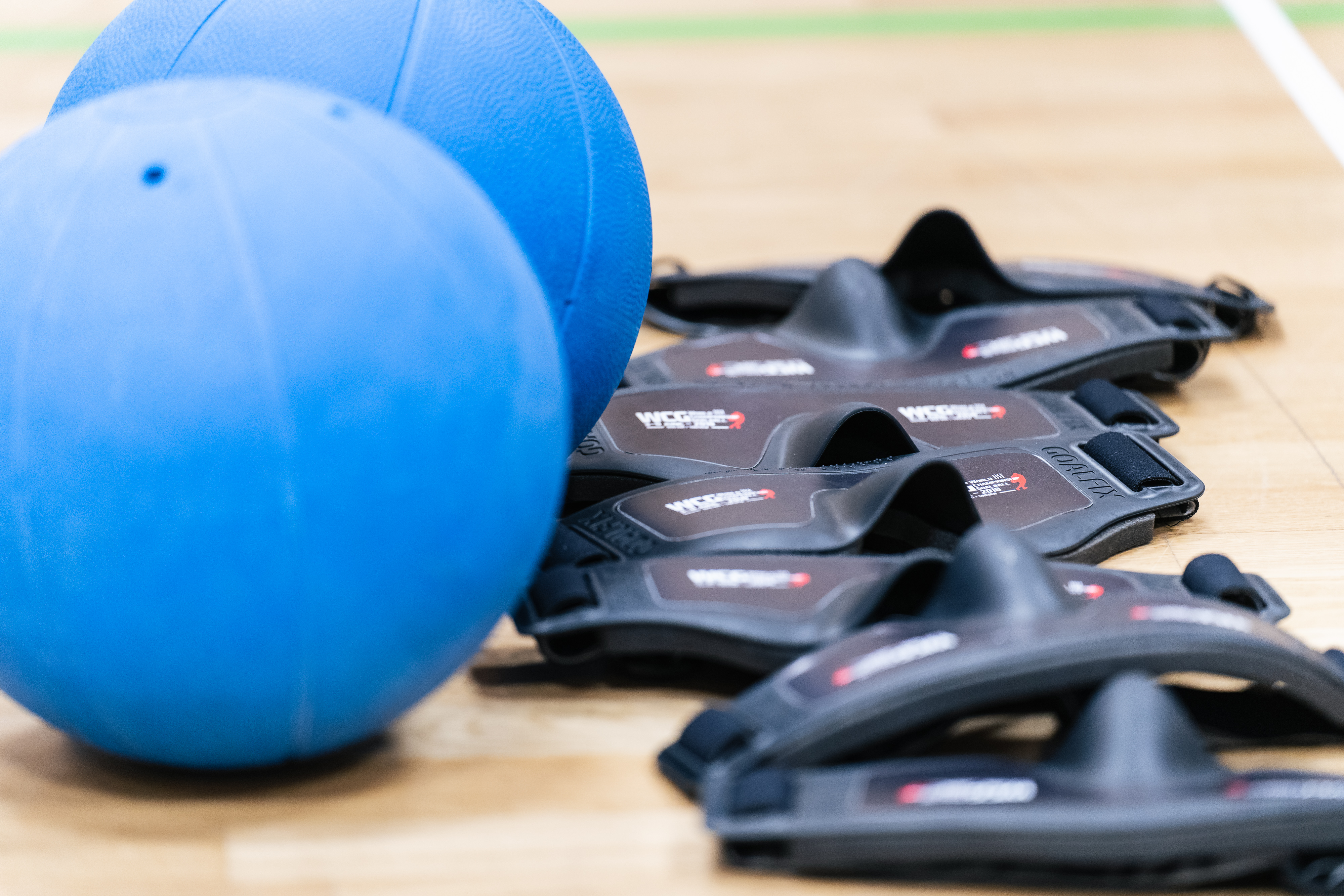 Goalball-bollar och ögonbindlar på ett golv.