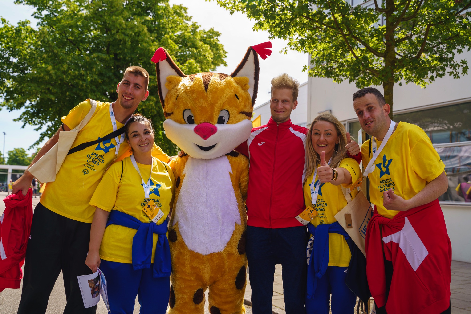 Maskoten Speci-Lo är omgiven av glada idrottare på Special Olympics Games i Malmö.