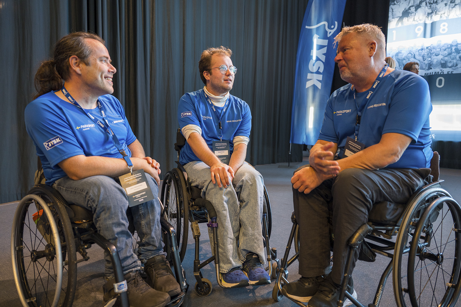 Tre personer i rullstol pratar med varandra i en paus på konferensen.