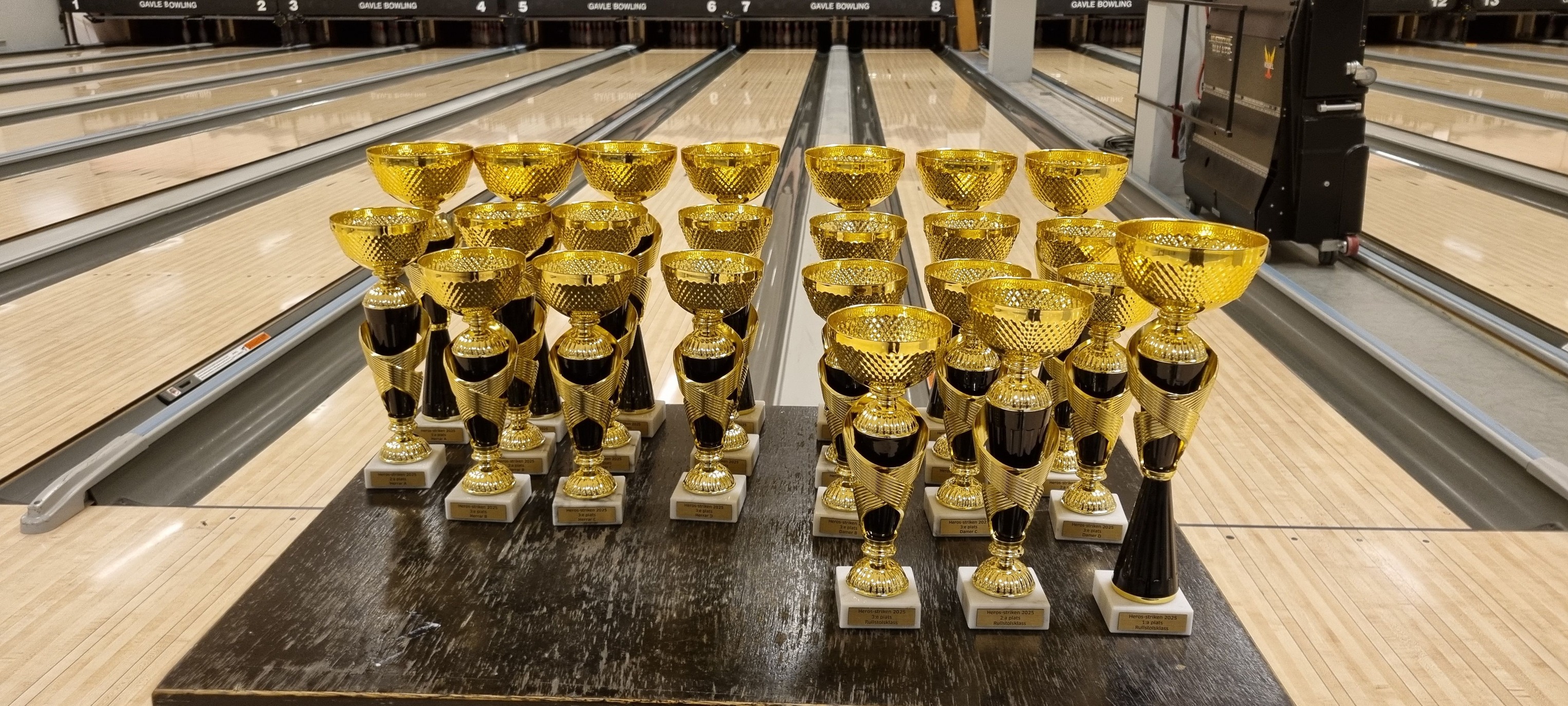 Bild lånad från X-Y Strikens facebooksida. Bildbeskrivning: Foto på flera guldiga pokaler med bowlingbanor i bakgrunden