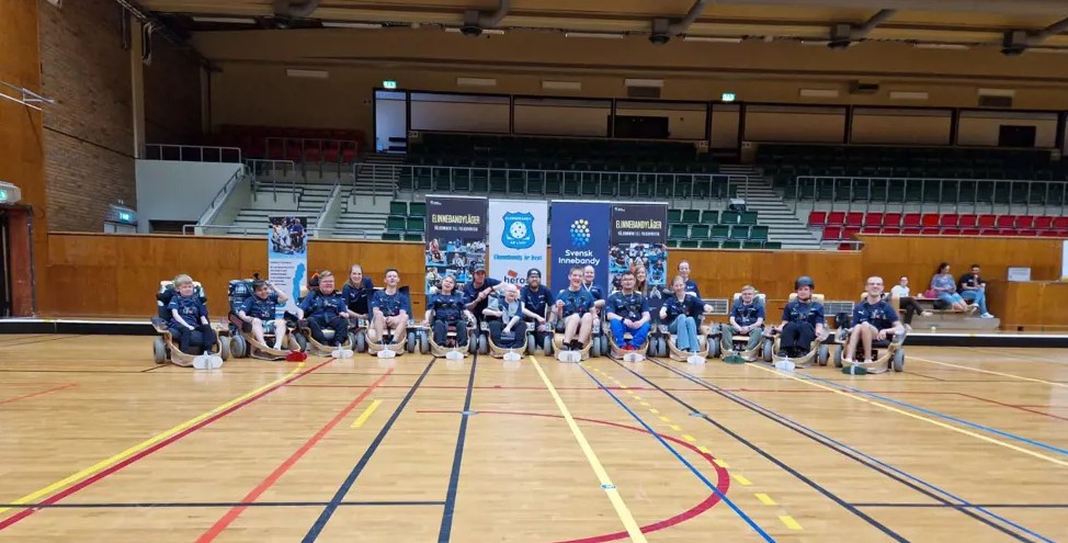 Gruppbild på deltagarna på lägret. De har alla blå t-shirt på sig och sitter i sina elinnebandystolar.