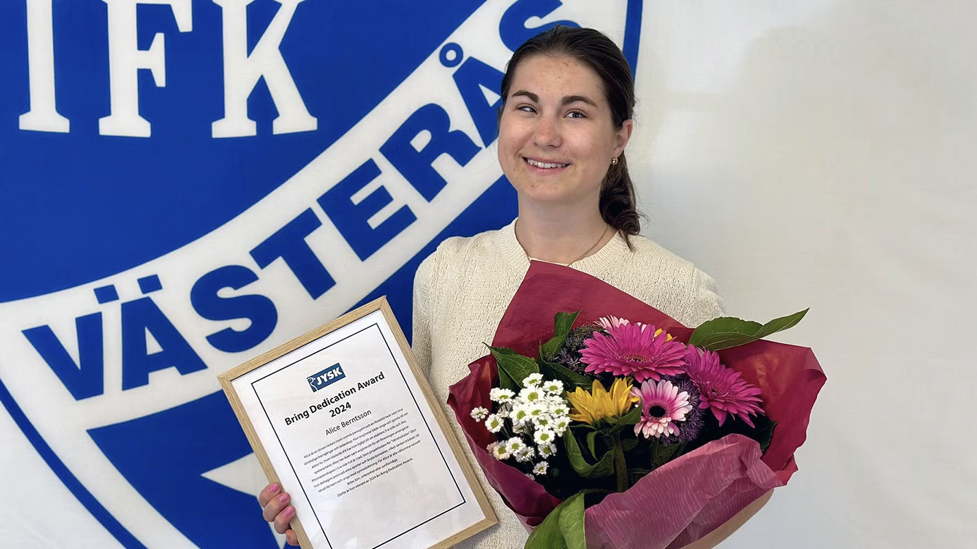 Alice Berntsson håller upp diplom och blombukett efter att ha mottagit priset i fjol.