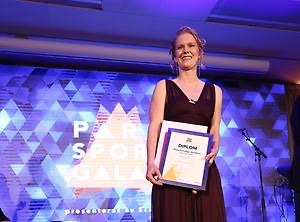 Maja Reichard på scen på Svenska Parasportgalan 2017, iförd mörk långklänning. Hon håller i diplomet för "Årets kvinnliga idrottare". Foto.